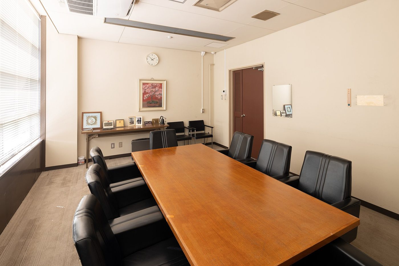 An empty meeting room with a long table and rows of chairs