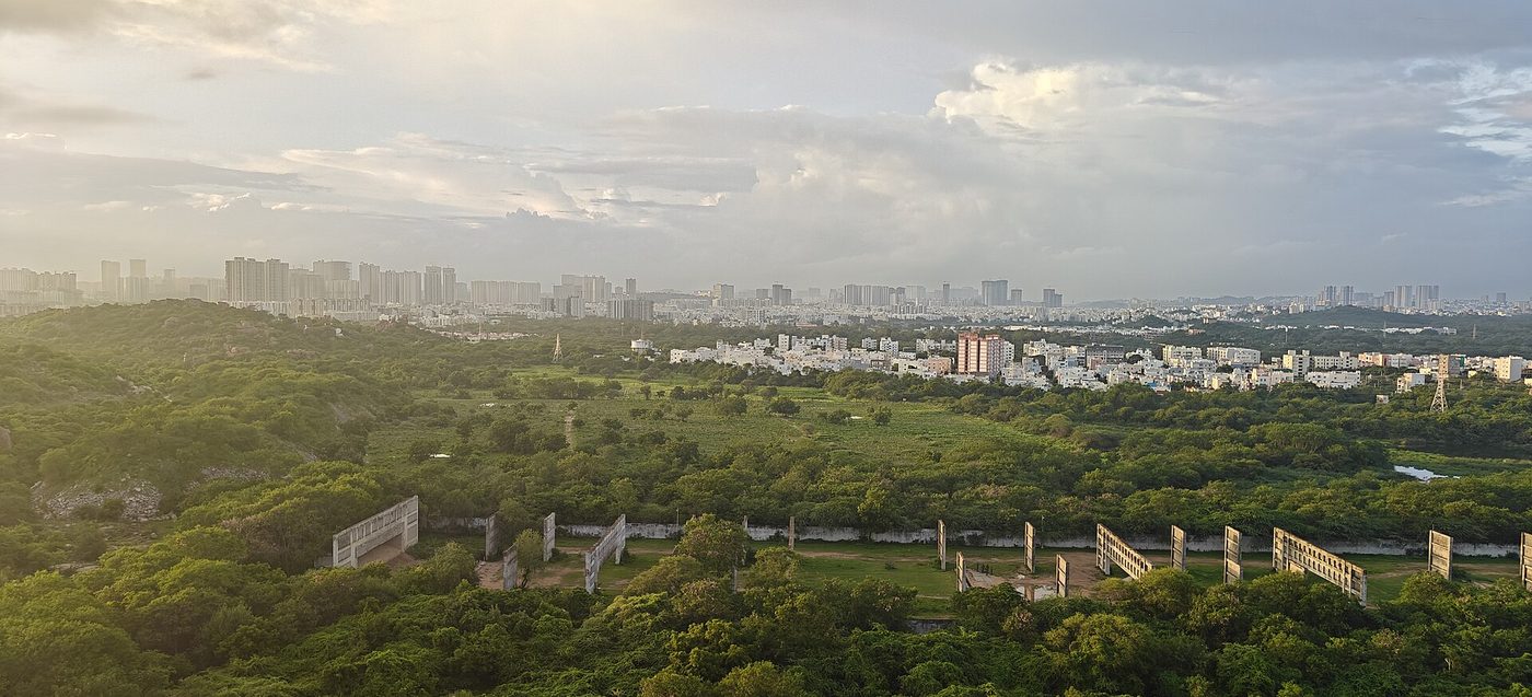 Hyderabad city rooftops and lake seen at dusk under a heavy sky