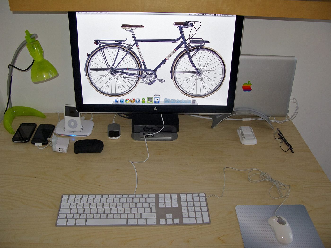 An open laptop on a desk beside a notebook