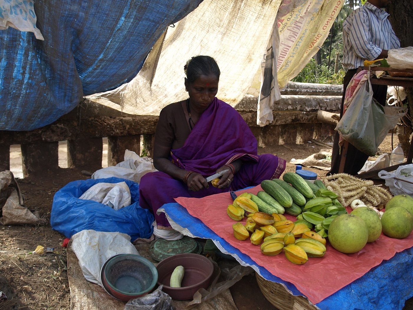 A vegetable vendor arranging produce at a market stall