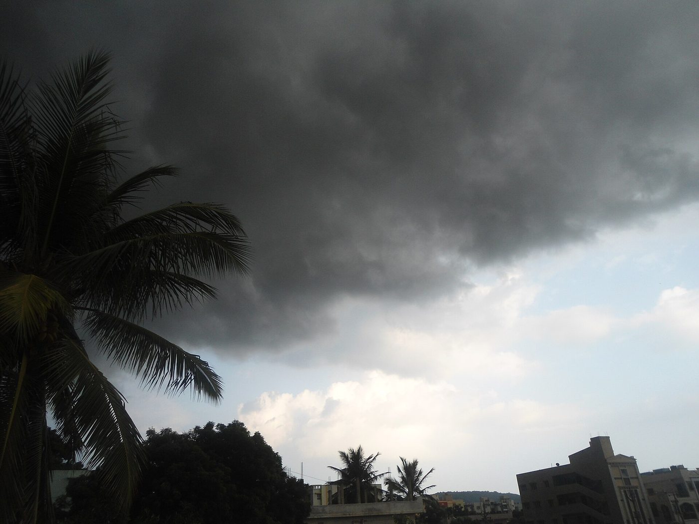 Towering monsoon storm clouds building over rooftops