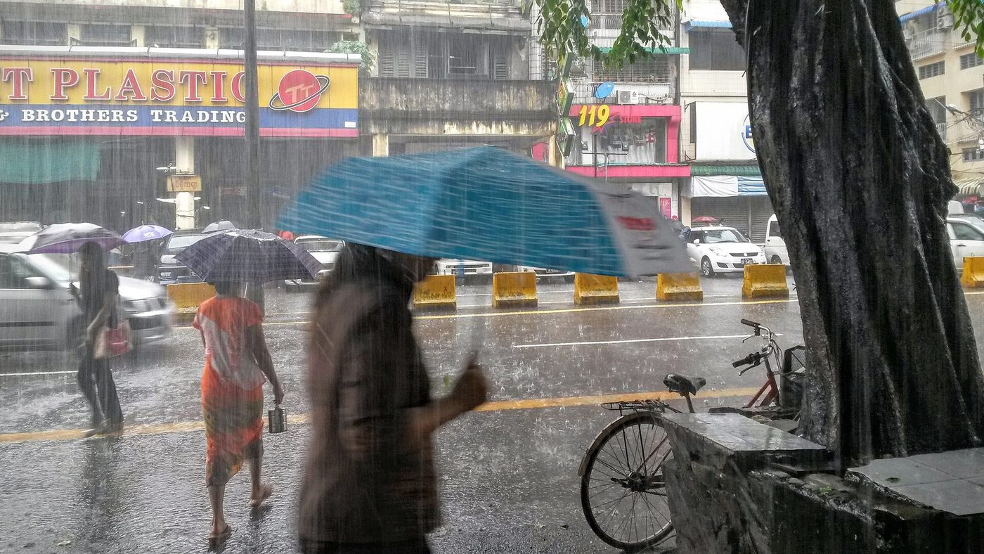 A person sheltering under an umbrella in pouring rain
